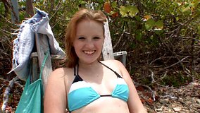 A smiling blue eyed honey is playing with a dick on the beach