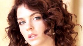 A girl with curly hair is opening up her legs to show off her pussy